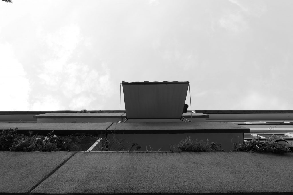 Ein Balkon mit Markise, von unten fotografiert.