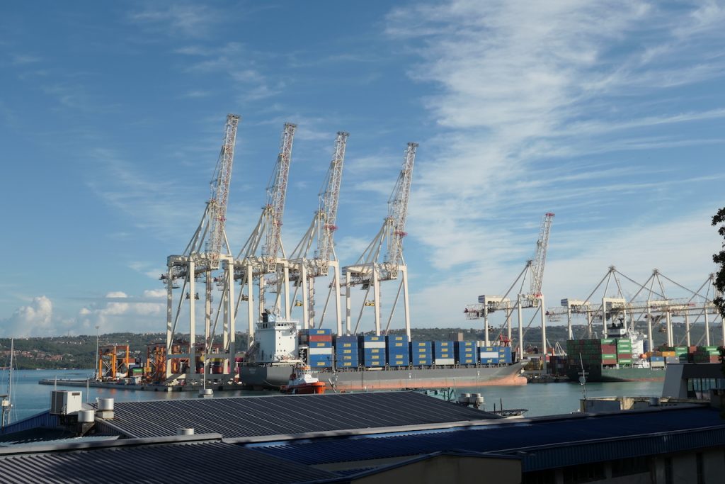 Ein Containerschiff vor den Kränen des Hafens Koper.