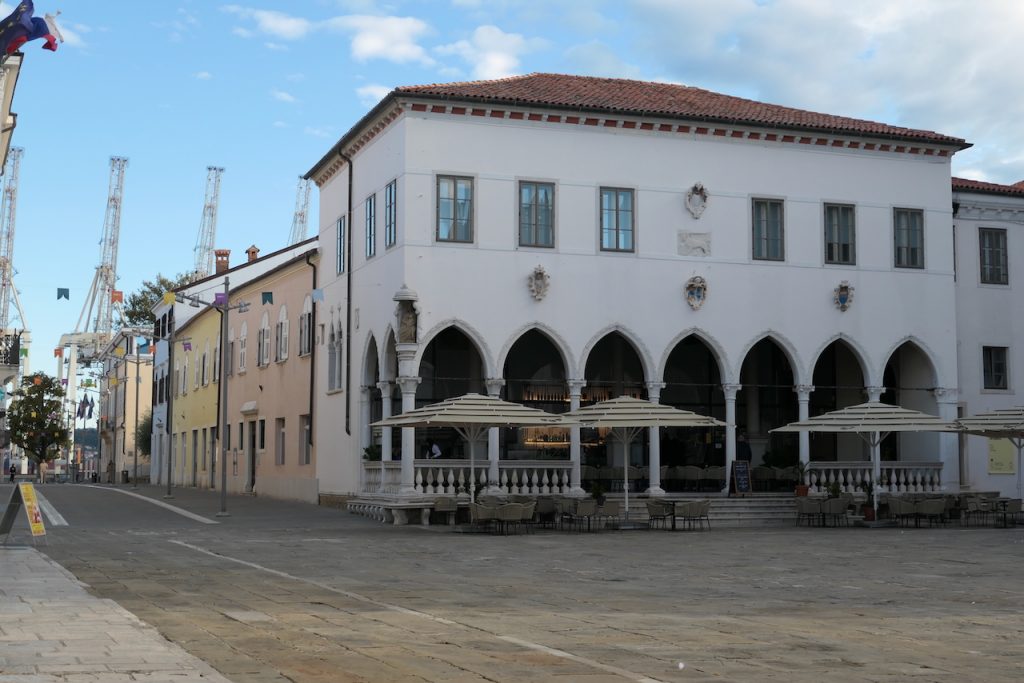 Loggia-Palast mit Café. Im Hintergrund Kräne des Hafens.
