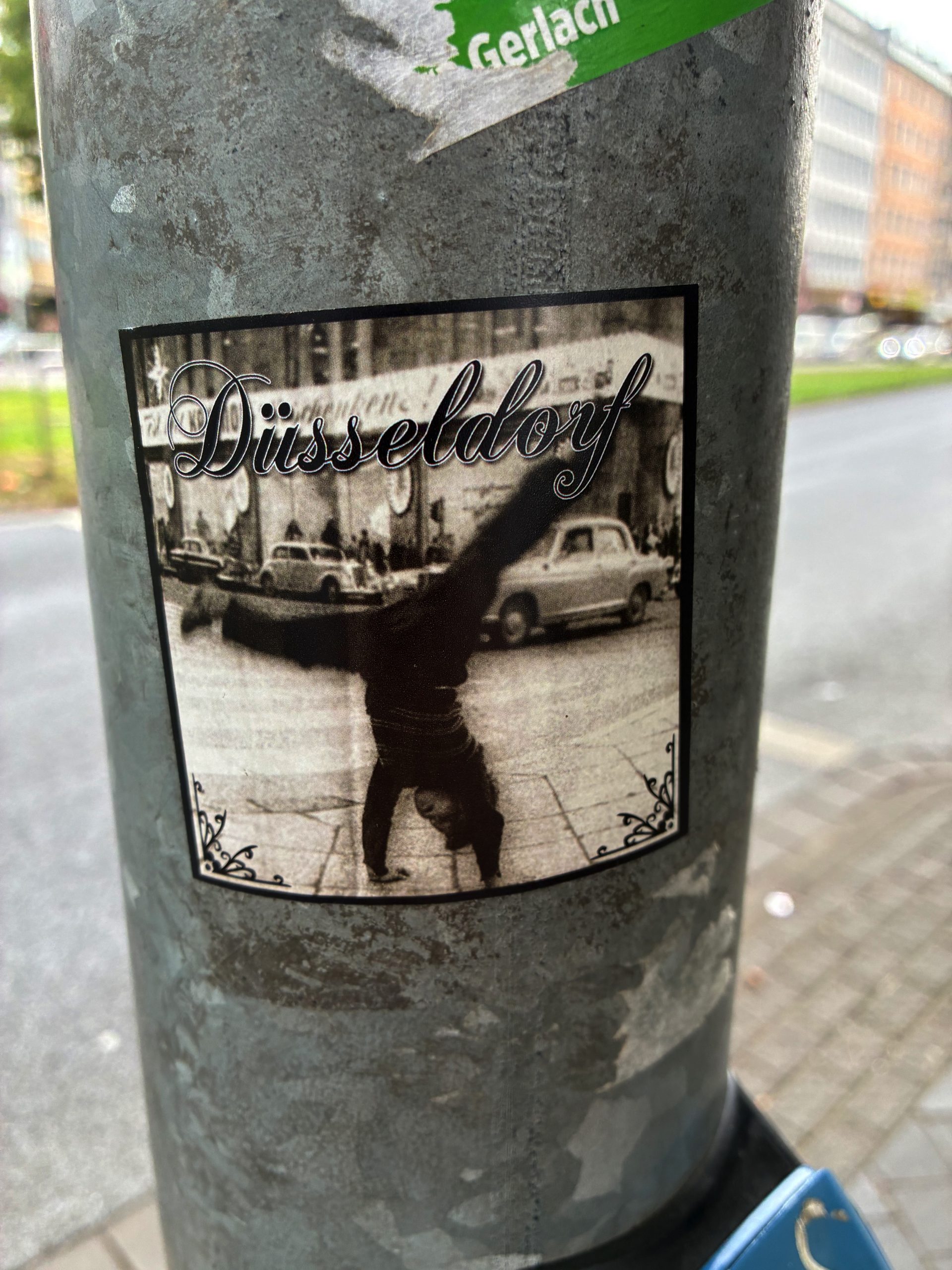 s/w-Foto einer Person, die ein Rad schlägt. Im Hintergrund eine Straßenszene