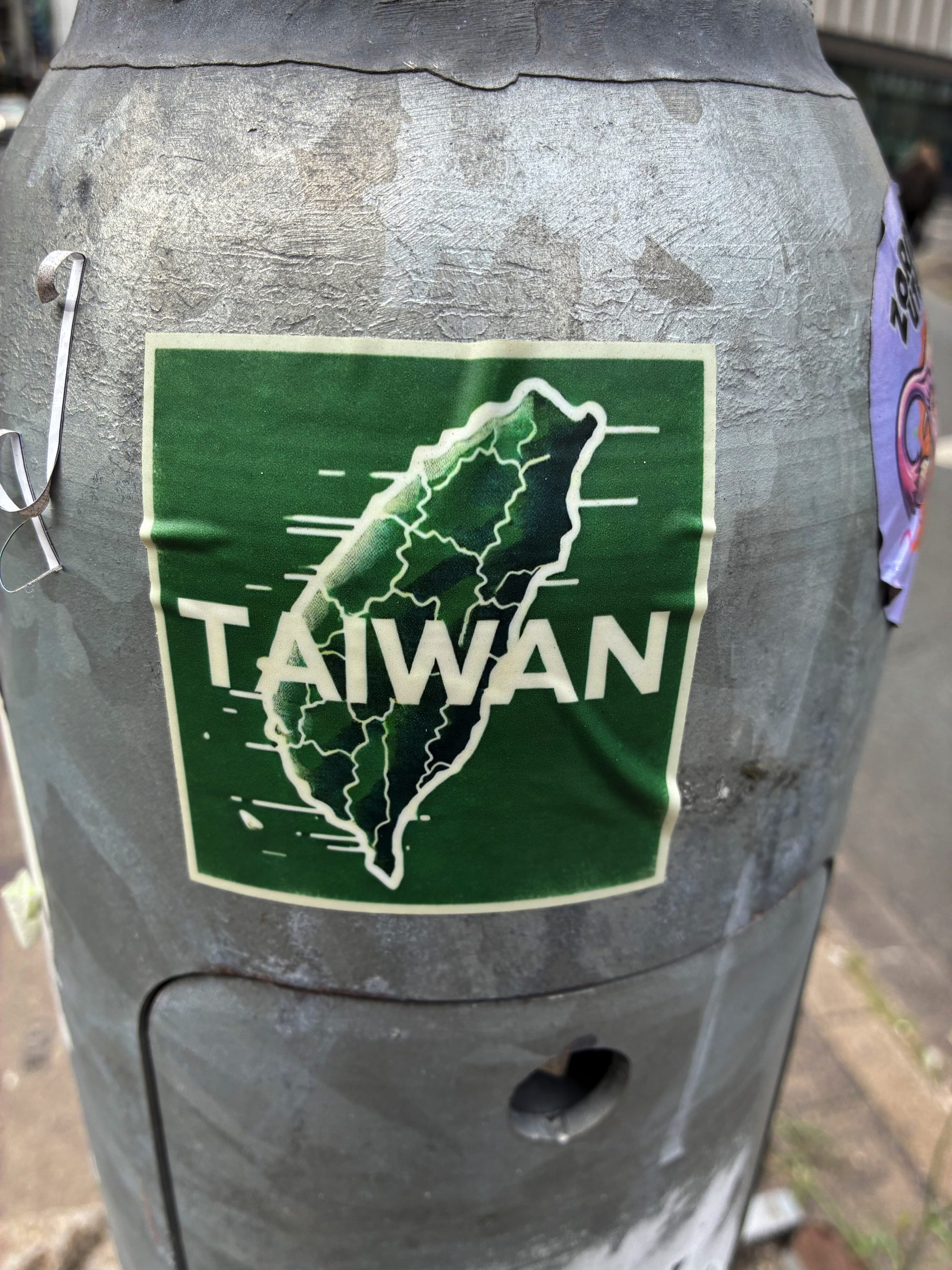 Brauner Sticker mit dem Umriss der Insel Taiwan. Darüber in großer, weißer Schrift: TAIWAN